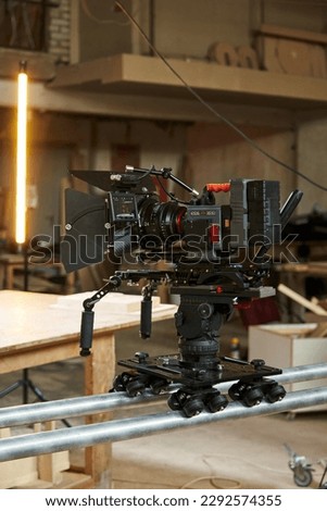 a professional video camera stands on a camera trolley on rails on a film set
