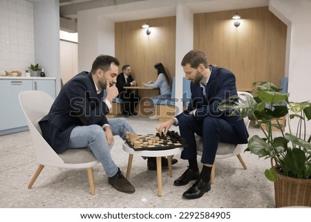 Two business professional men playing chess in office cafe, sitting at board, moving pieces, enjoying break, smart game, hobby, leisure time, entertainment, training intelligence, strategic skills