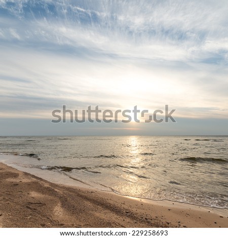 Shoreline of Baltic sea beach with rocks and sand dunes under clouds