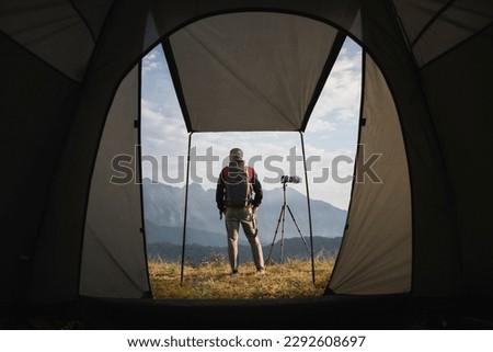 Photographer standing in front of a camping tent. Travel concept adventure active vacations outdoor