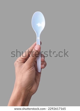 Isolated of a man’s hand holding a spoon to cook food illustration. hand grabbing a plastic spoon on grey background.