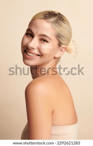 Beautiful smiling woman with tone cream lines on her face, girl with perfect makeup on white background, Skin care concept. Royalty-Free Stock Photo #2292621283
