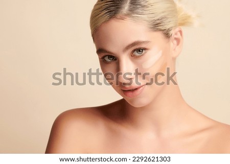 Beautiful smiling woman with tone cream lines on her face, girl with perfect makeup on white background, Skin care concept. Royalty-Free Stock Photo #2292621303