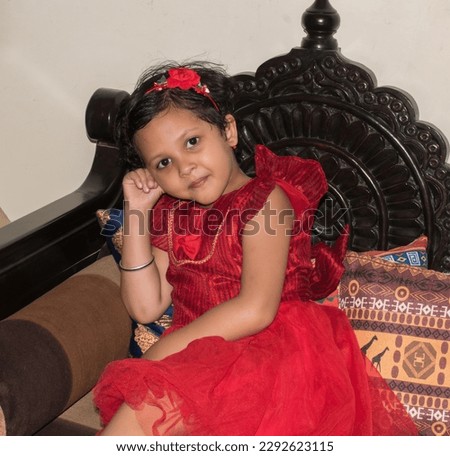 Cute little happy Indian girl in red frock and hair band. Ready for party