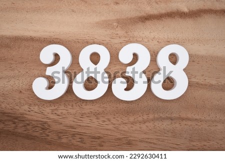 White number 3838 on a brown and light brown wooden background.