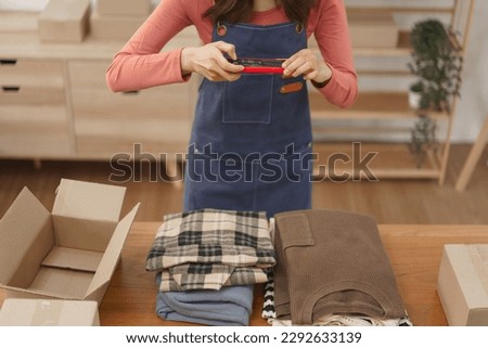 Online business merchant concept, Women entrepreneur taking photo clothes before packing in the box.