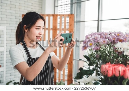 Beautiful florist taking pictures of beautifully arranged vase flowers with bright face in flower shop to promote the store.
