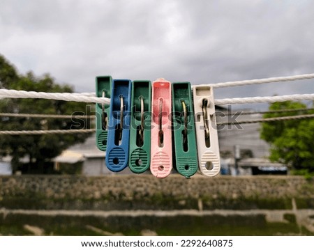 Multi-colored old plastic clothespins hanging on a the thread. The color of the clothespins have been faded.