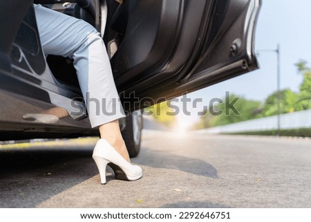 Happy cheerful Asian woman getting in or getting out of the car from driver position, female driver smiles and looks at camera. Royalty-Free Stock Photo #2292646751
