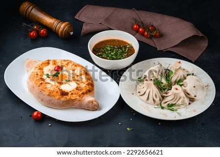 Georgian food khachapuri with egg, cherry tomato, butter and cheese, manti with meat and beef kharcho soup. Royalty-Free Stock Photo #2292656621