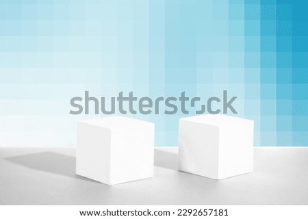  Two cement cubic podiums on a blue and white pixelated background. Mockup for the demonstration of cosmetic products.