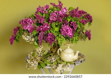 Nice bouquet of lilacs in a vases on a background of warm colors.