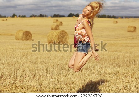 beautiful blonde jumps in sloping field sun happiness