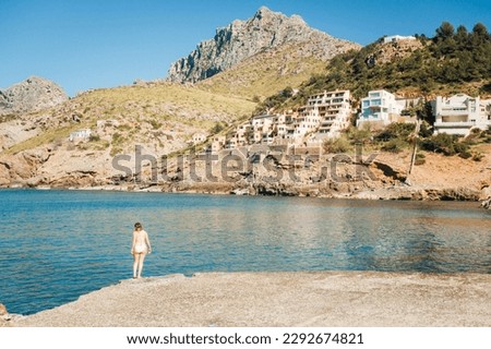 A young woman on a beach in the Balearic Islands. A woman in a bikini in Majorca. Bathing in the Mediterranean Sea. Holidays in the sun. Alone at the sea. Tropical sea. Turquoise blue sea. 