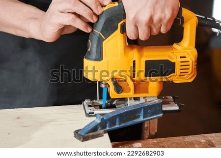 caucasian worker's hands adjust the jigsaw before starting work Royalty-Free Stock Photo #2292682903