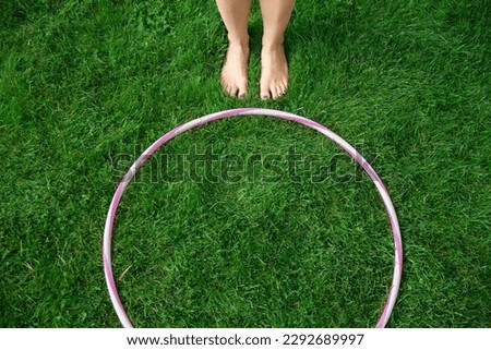 sport, leisure and fitness stuff concept - close up of hula hoop and woman's feet on grass