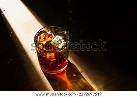 Dramatic top view of ice cubes falling in a glass of whiskey Royalty-Free Stock Photo #2292699519