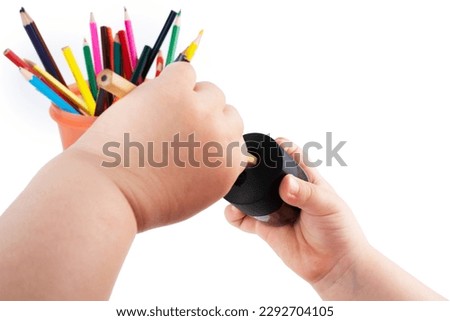 Sharpen pencils. The child's hands sharpen a pencil at school in the lesson. In the background, a sketchbook and colored pencils on the table. High quality photo