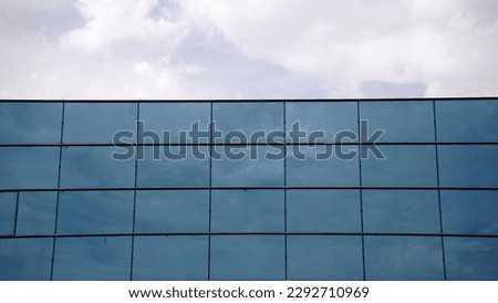 frontal glass facade against cloudy sky