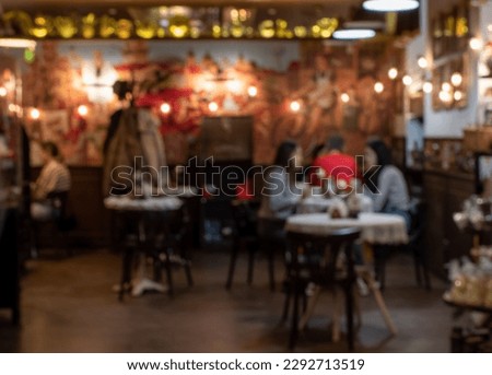 Blurred image of cozy cafe with color illumination and silhouettes of visitors at the tables Royalty-Free Stock Photo #2292713519