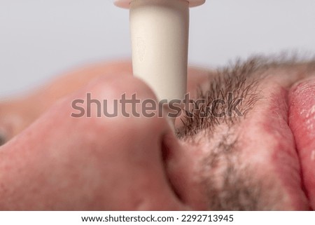 Red nose and gray beard macro photo picture with medicine white dropper on male face and white background