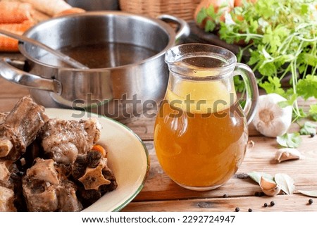 Homemade Beef Bone Broth in glass on rustic wooden table. Bones contain collagen, which provides the body with amino acids, which are the building blocks of proteins