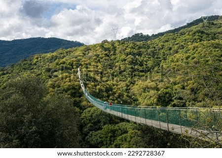 Bridge in Mazamitla, Long suspension bridge over green and cloudy jungle Royalty-Free Stock Photo #2292728367