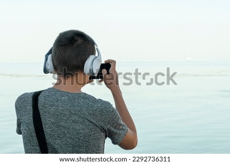 a young man takes pictures on his phone on the seashore