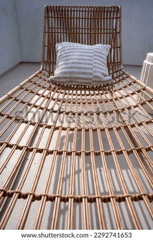 Close up on a wicker sun lounger and pillow on a sun deck.