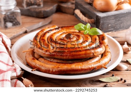 The picture shows a homemade sausage, rolled into rings, which lies on wooden table.