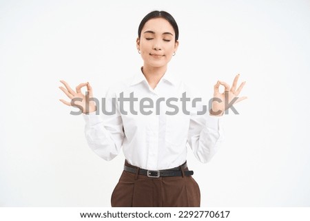 Wellbeing and workplace. Young asian businesswoman meditates, keeps calm, relaxes after work, white background.