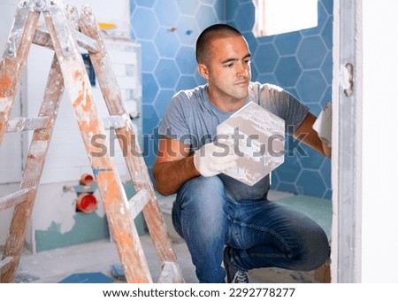 Caucasian man installing bathroom tile during home improvement works. Royalty-Free Stock Photo #2292778277