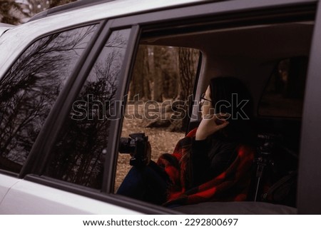 photographer woman sitting in the car enjoying the view of a park during winter time