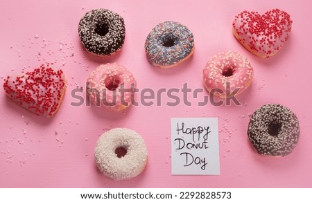 Donuts doughnuts with chocolate, marshmallow and sugar sprinkles on pink background, top view. Colorful carnival or birthday party card. Happy National donut day Concept.