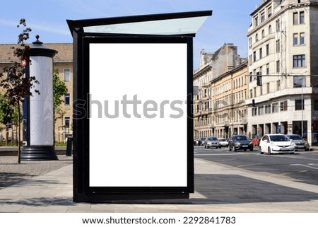 bus shelter blank ad panel. billboard display. empty white lightbox sign at busstop. glass structure. transit station. mockup base. urban street with traffic. park setting. bus shelter advertising