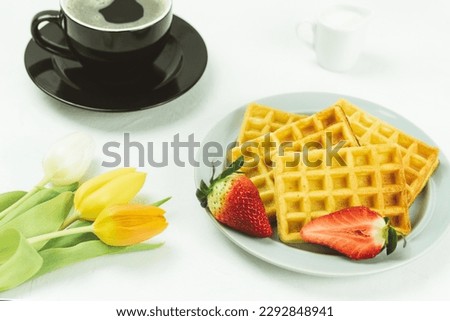 Fresh tulips and Belgian fruit waffles, top view. Tasty breakfast. Breakfast for a loved one. Homemade waffles on a plate. Background with copy space