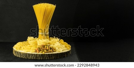 A variety of pasta and spaghetti on a dark background. Raw pasta for cooking Italian cuisine on a wooden table on a dark background. copy space
