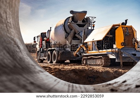 Concrete mixer truck delivers concrete to the pump for pouring piles. Concrete pump at the construction site. Close-up of concrete delivery Royalty-Free Stock Photo #2292853059