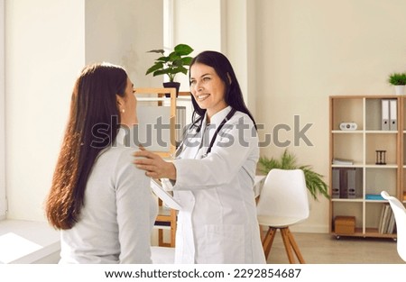 Friendly woman doctor supporting her female patient during medical examination in hospital. Smiling lady in white coat talking to young woman, calming her down and telling about effective treatment Royalty-Free Stock Photo #2292854687