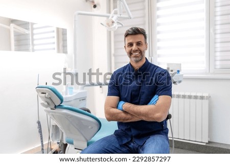 Dentist man smiling while standing in dental clinic. Portrait of confident a young dentist working in his consulting room Royalty-Free Stock Photo #2292857297