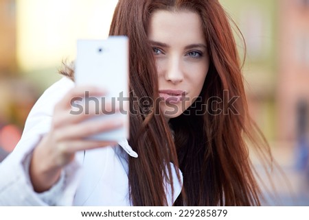 pretty young woman taking a picture on town
