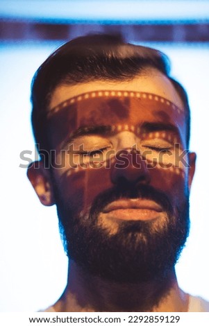 Portrait of a man holding developed photographic film in his hands in front of a light source and reviewing the captured footage