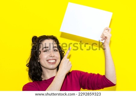 young smiling latin woman pointing with finger on white board isolated on yellow background