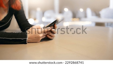 Young asian woman using smartphone during leisure time while sitting in cafe. The concept of using the phone is essential in everyday life