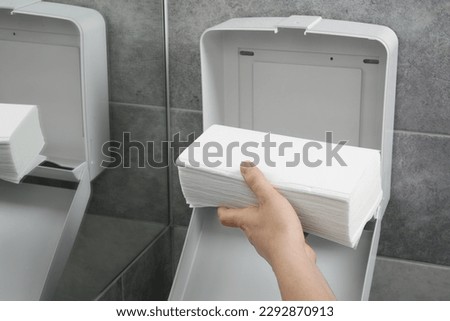 Woman putting new fresh paper towels into dispenser in bathroom, closeup Royalty-Free Stock Photo #2292870913