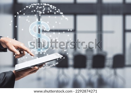 Close up of businessman hand pointing at tablet with glowing dollar sign inside polygonal sphere on blurry office interior background. World currency and technology concept. Double exposure