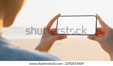 Young woman hand holding smartphone with taking photo on beach, Take your screen to put on advertising. Summer vacation concept.
