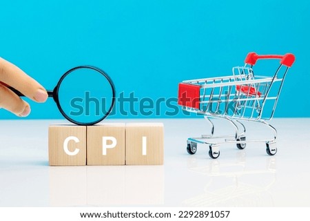 CPI - Consumer Price Index symbol.Letter block in word CPI abbreviation of consumer price index with a magnifying glass in woman's hand near empty shopping cart on blue background