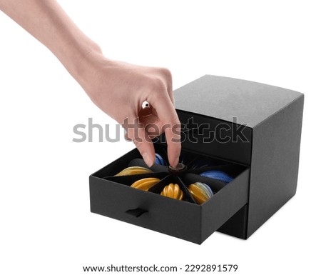 Woman taking delicious chocolate candy from black box on white background, closeup