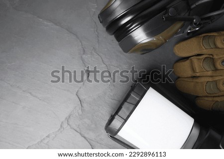 Camping lantern, tactical glove and headphones on gray background, flat lay with space for text. Military training equipment